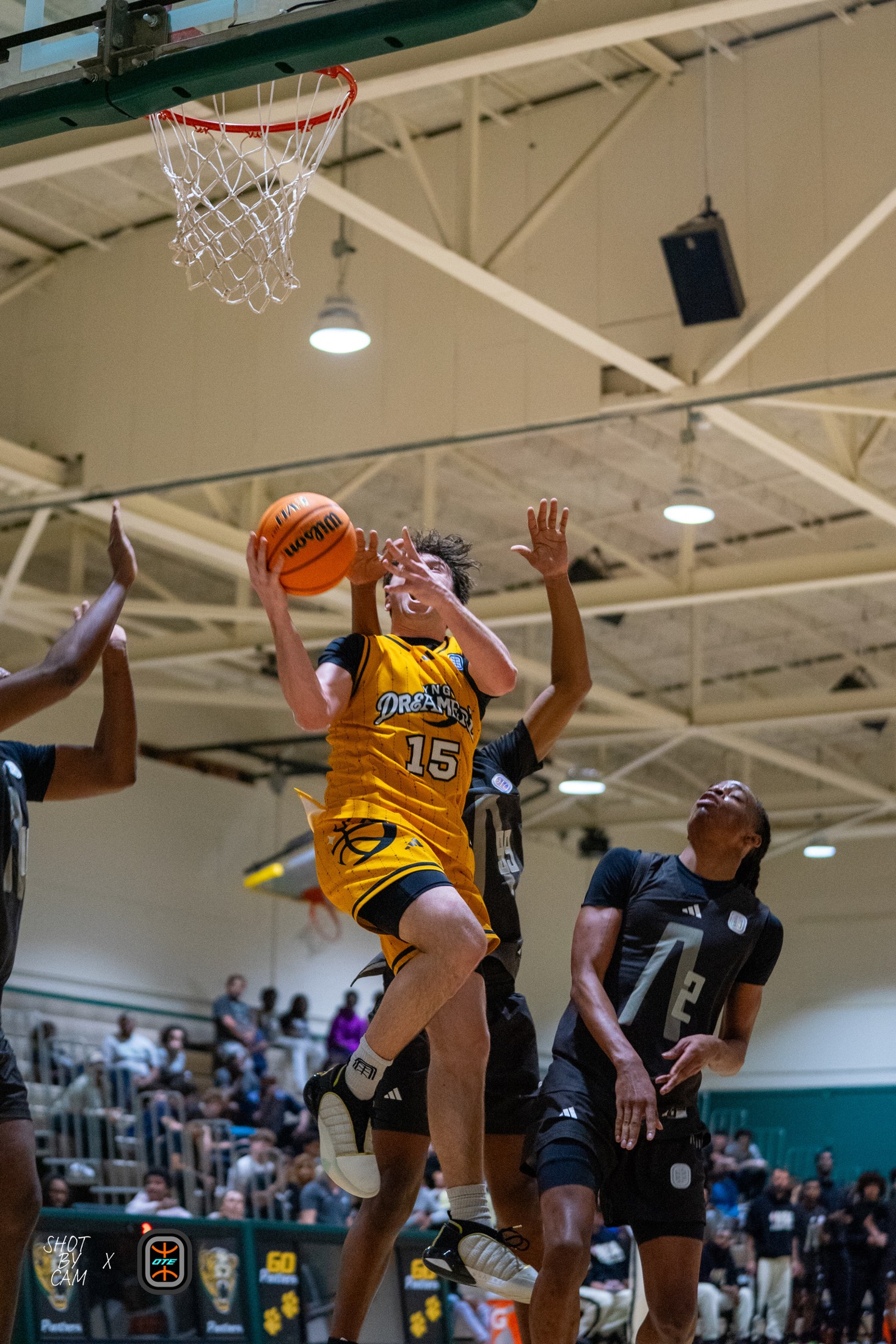 Basketball player finishing at the rim in a packed gym