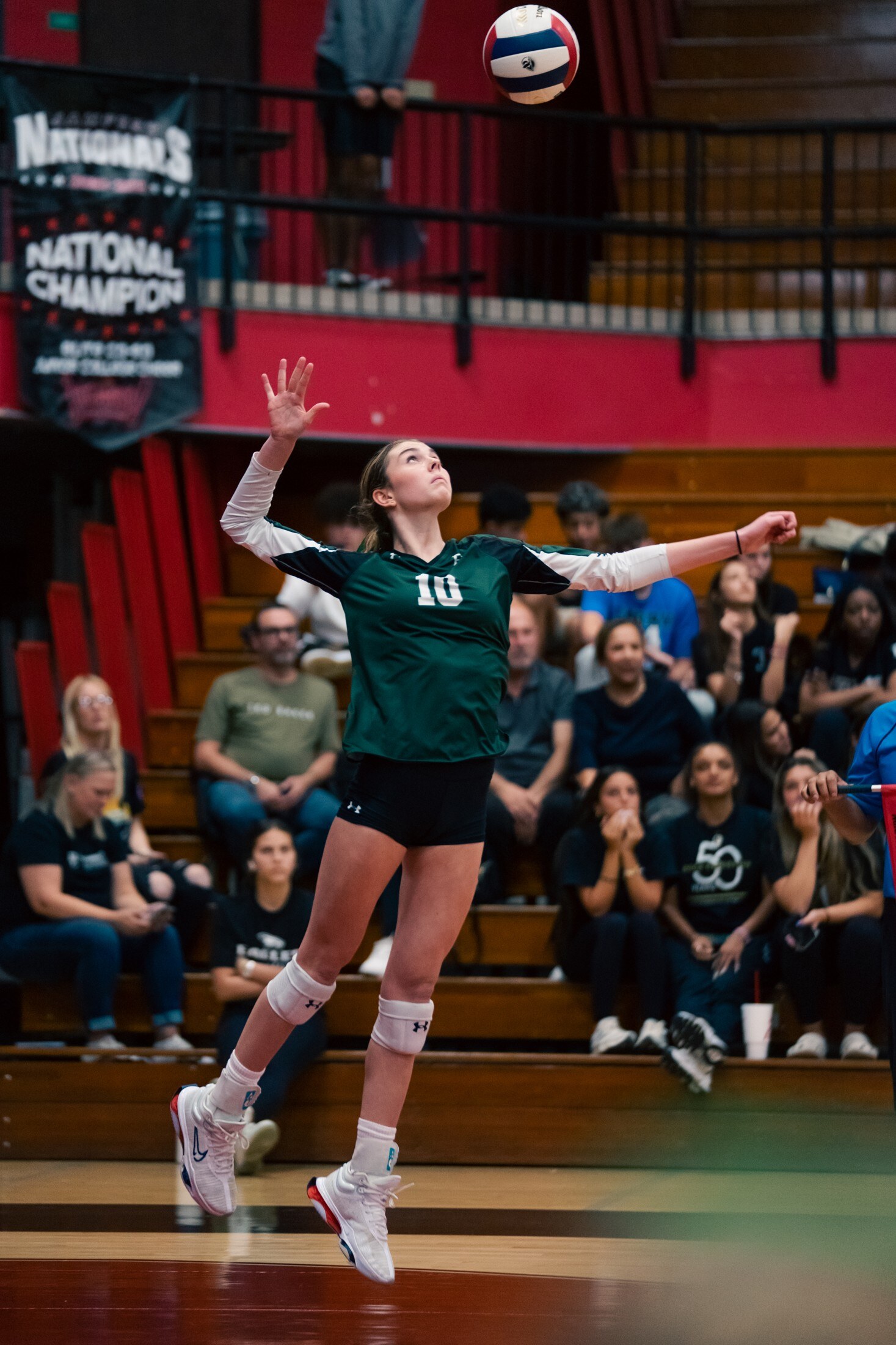 Volleyball player serving under championship banners