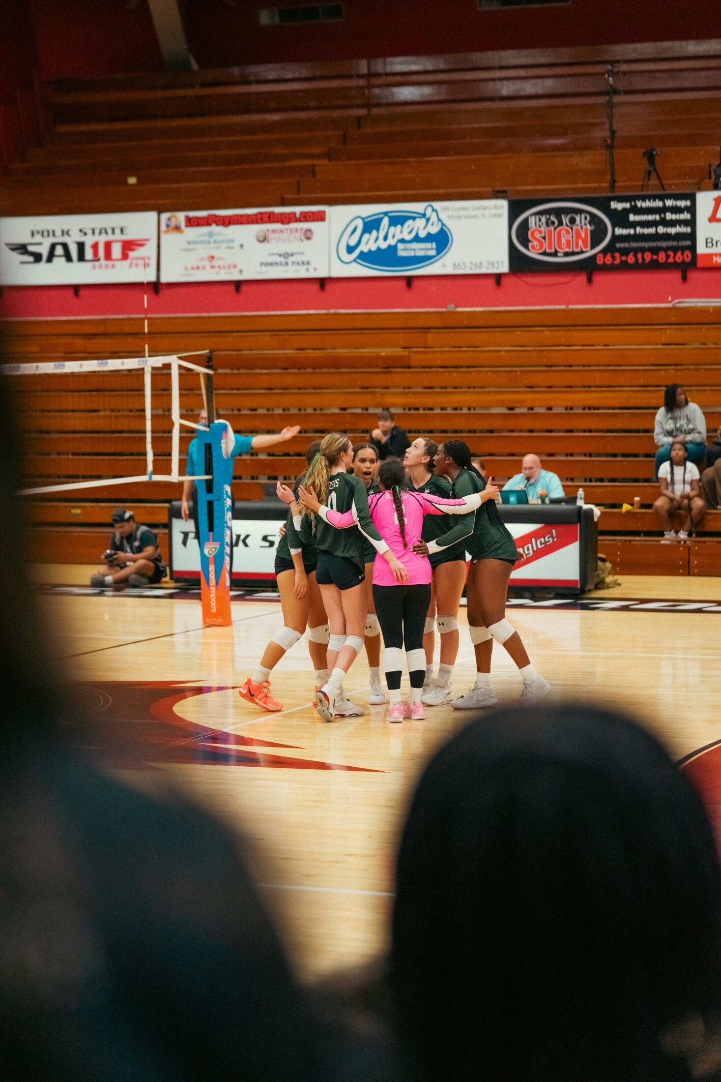 Volleyball team huddling at midcourt
